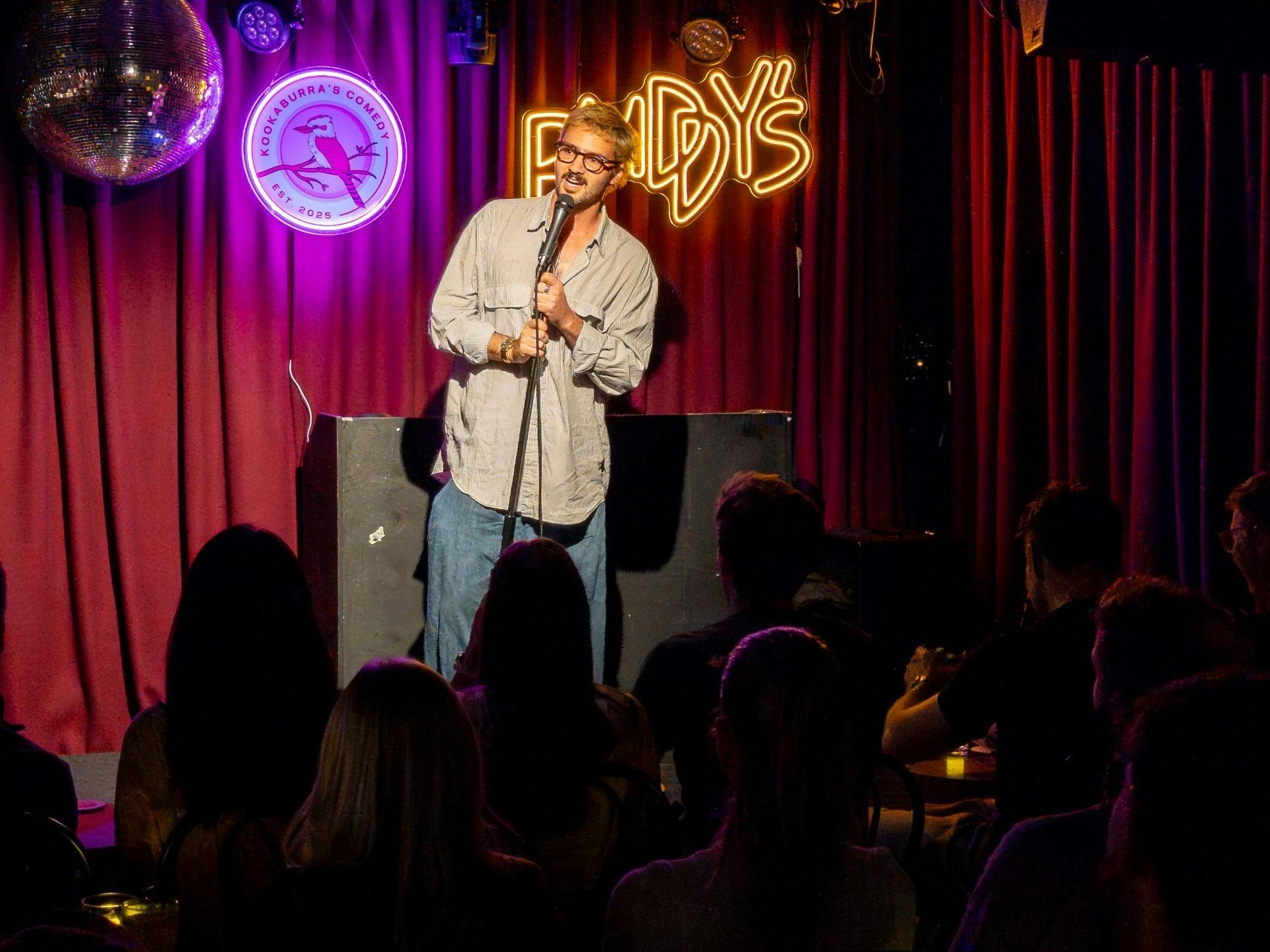 Friends in the audience laughing together at a stand-up comedy night