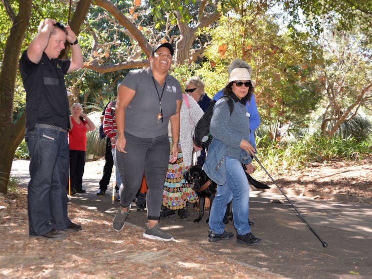 Blind, low vision and sighted travellers enjoying a walk through a bontacial garden with guides