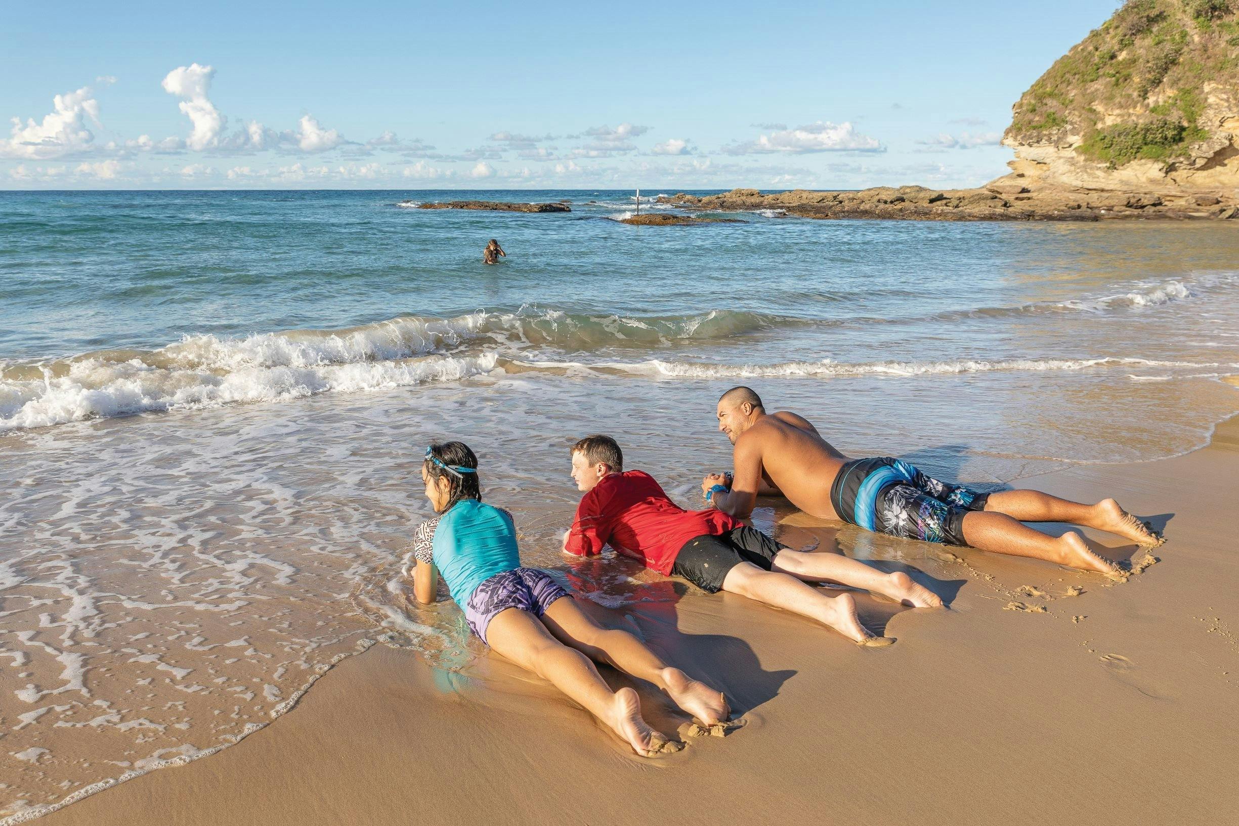 Dad and kids lying on the sand after a swim