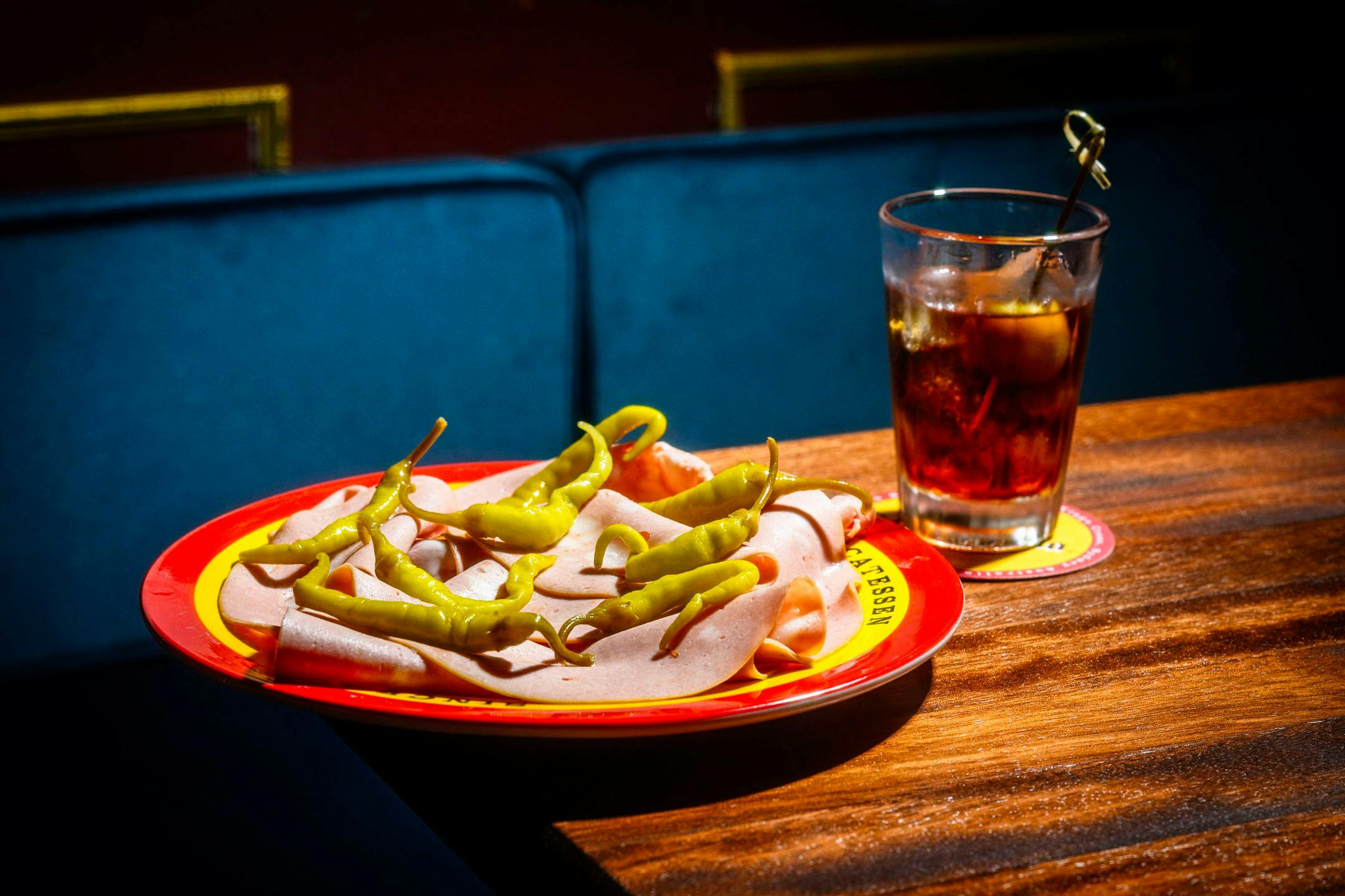 모르타델라, 나무 탁자 위의 그리퍼 흰색 접시, 아모로 음료, 뒤에 있는 파란색 벨벳 벤치