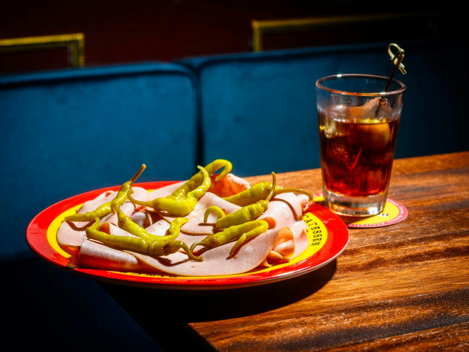 모르타델라, 나무 탁자 위의 그리퍼 흰색 접시, 아모로 음료, 뒤에 있는 파란색 벨벳 벤치