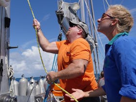 Hoisting the sail under crew guidance Ocean Free sail to Green Island & Great Barrier reef