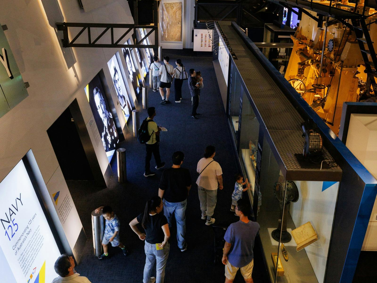 Visitors explore the Navy 125 exhibition, featuring historic portraits and maritime displays.