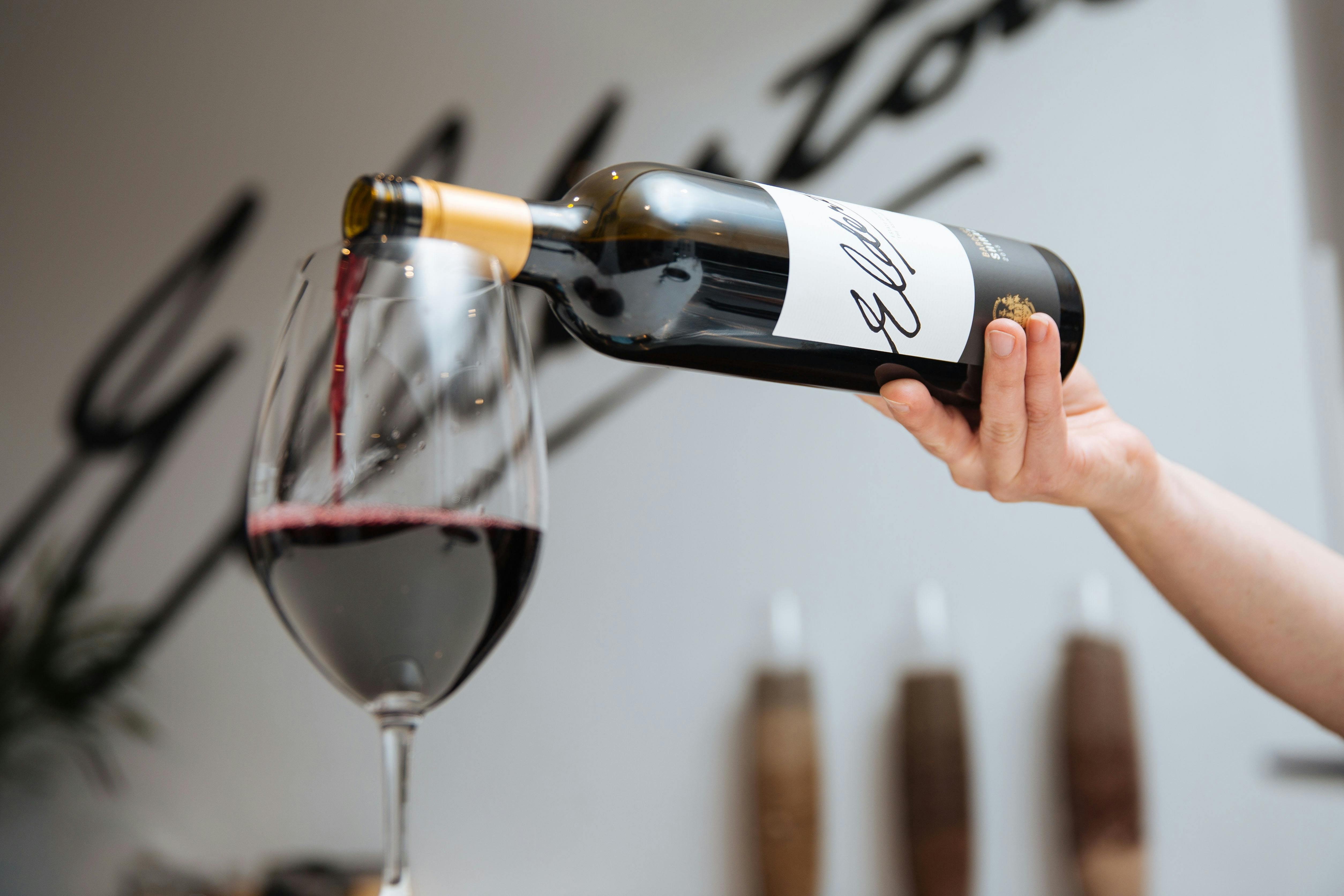 A glass of Barossa Shiraz being poured into a glass. The Elderton logo is in the background,
