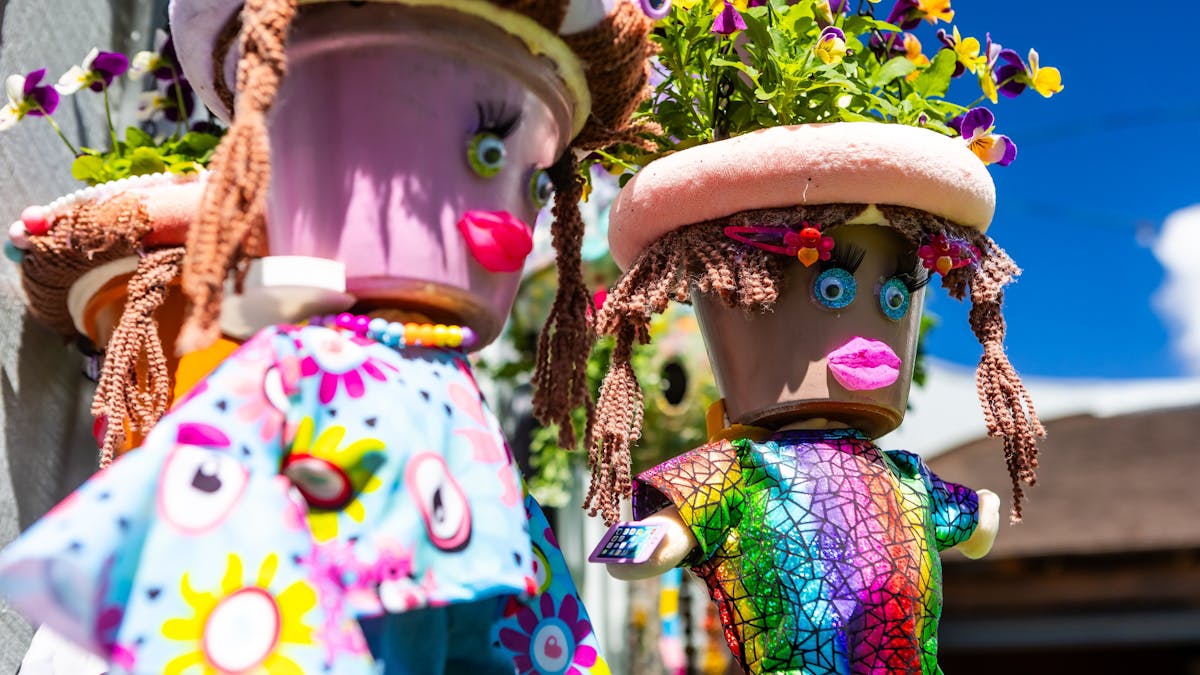 Hanging baskets with pots as faces and bodies hanging below designed to look like people.