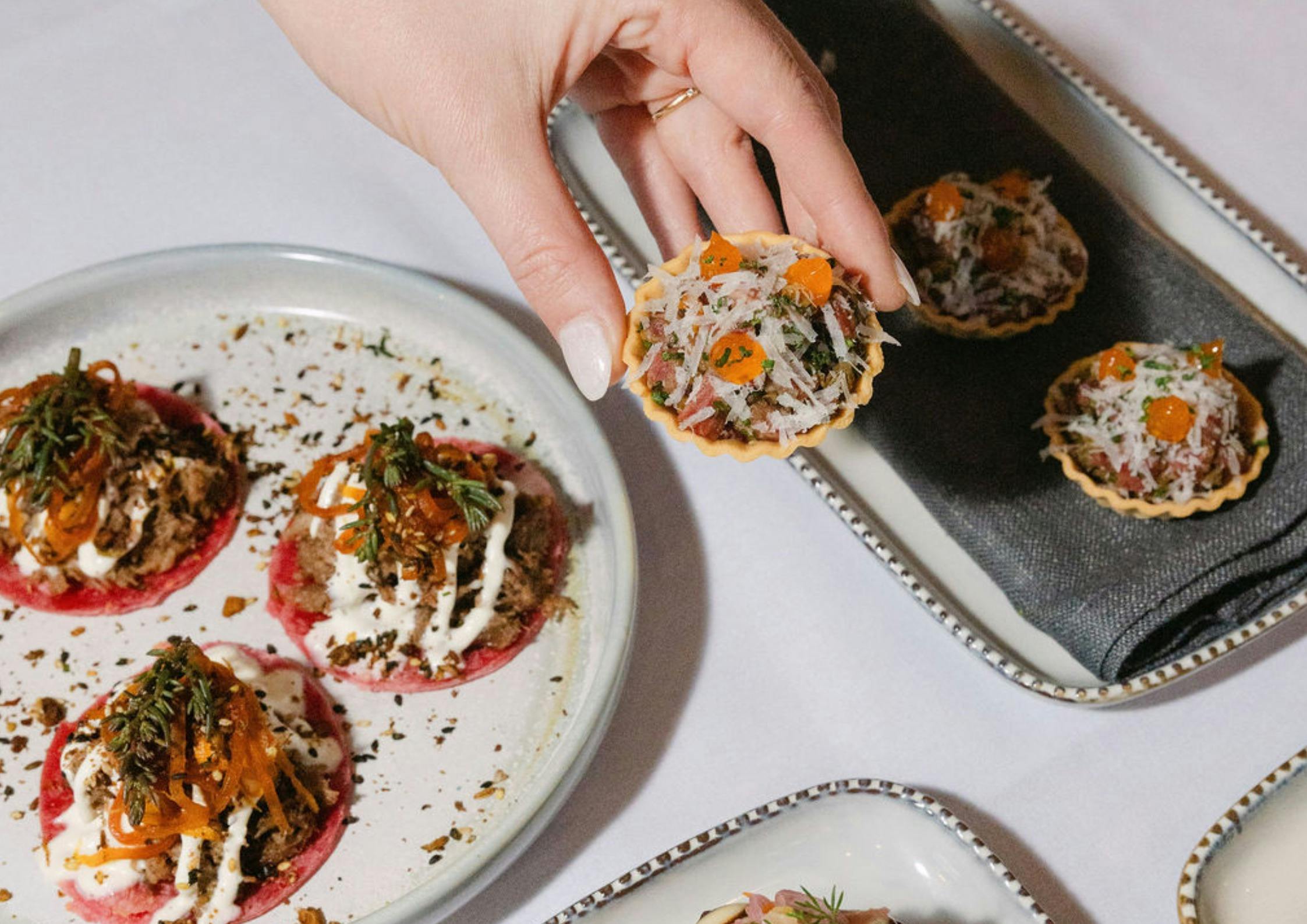 A hand holding a mini tartlet canape