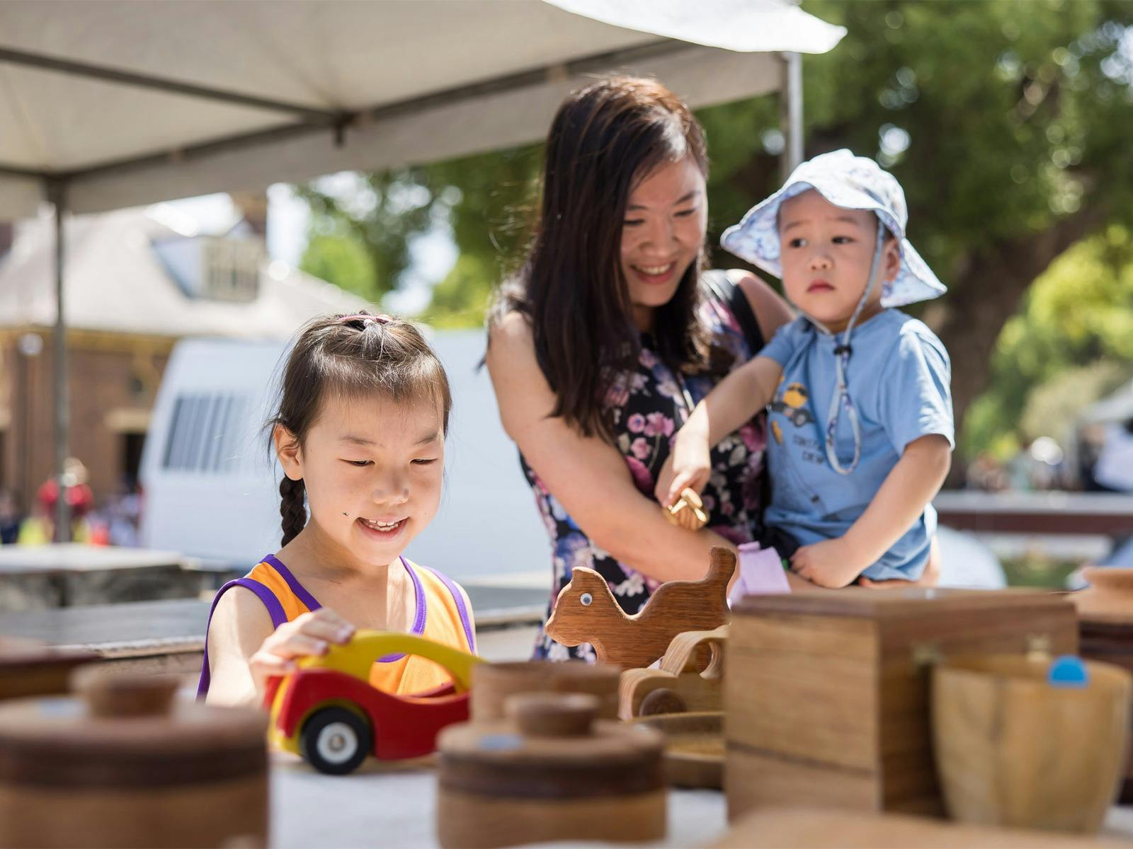 A woman and two children enjoy a sunny day at Foundation Day markets.