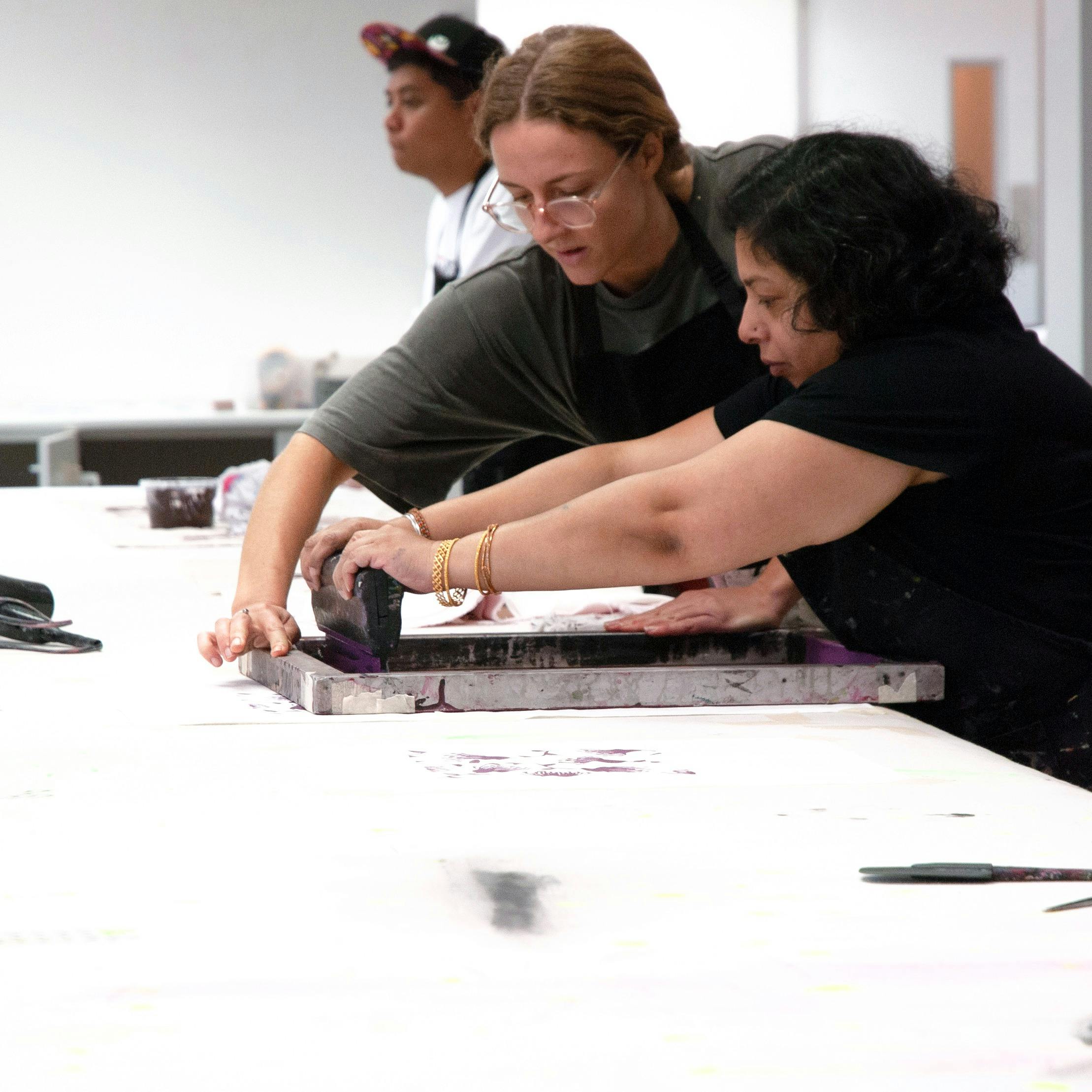 Two women hold a screen flat and squeegee