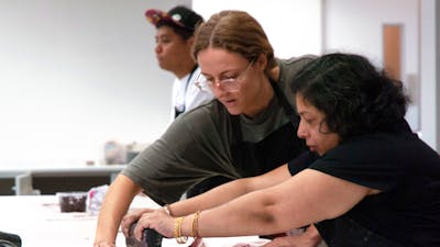 Two women hold a screen flat and squeegee