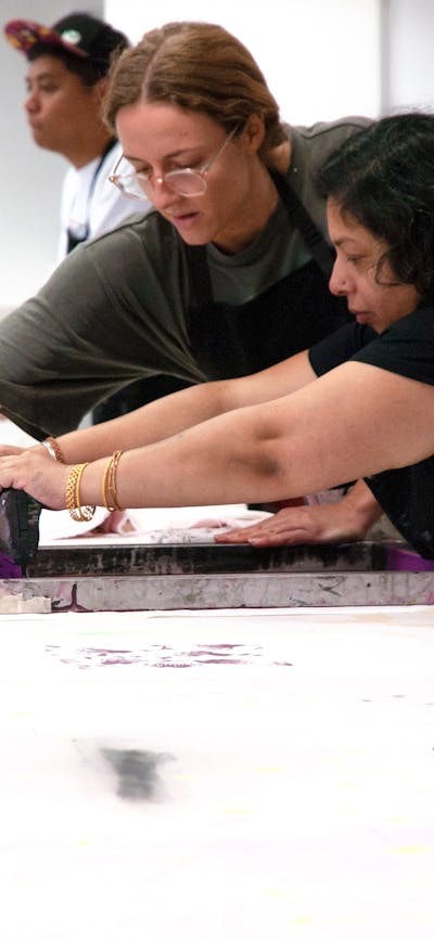 Two women hold a screen flat and squeegee