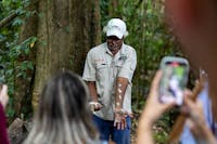 Kuku Yalanji Tribe Member demonstrating to visitors the use of local herbs while a guest photographs