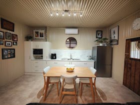 A picture of a scandi style 4 seater dining table, large stainless steel fridge and kitchen.