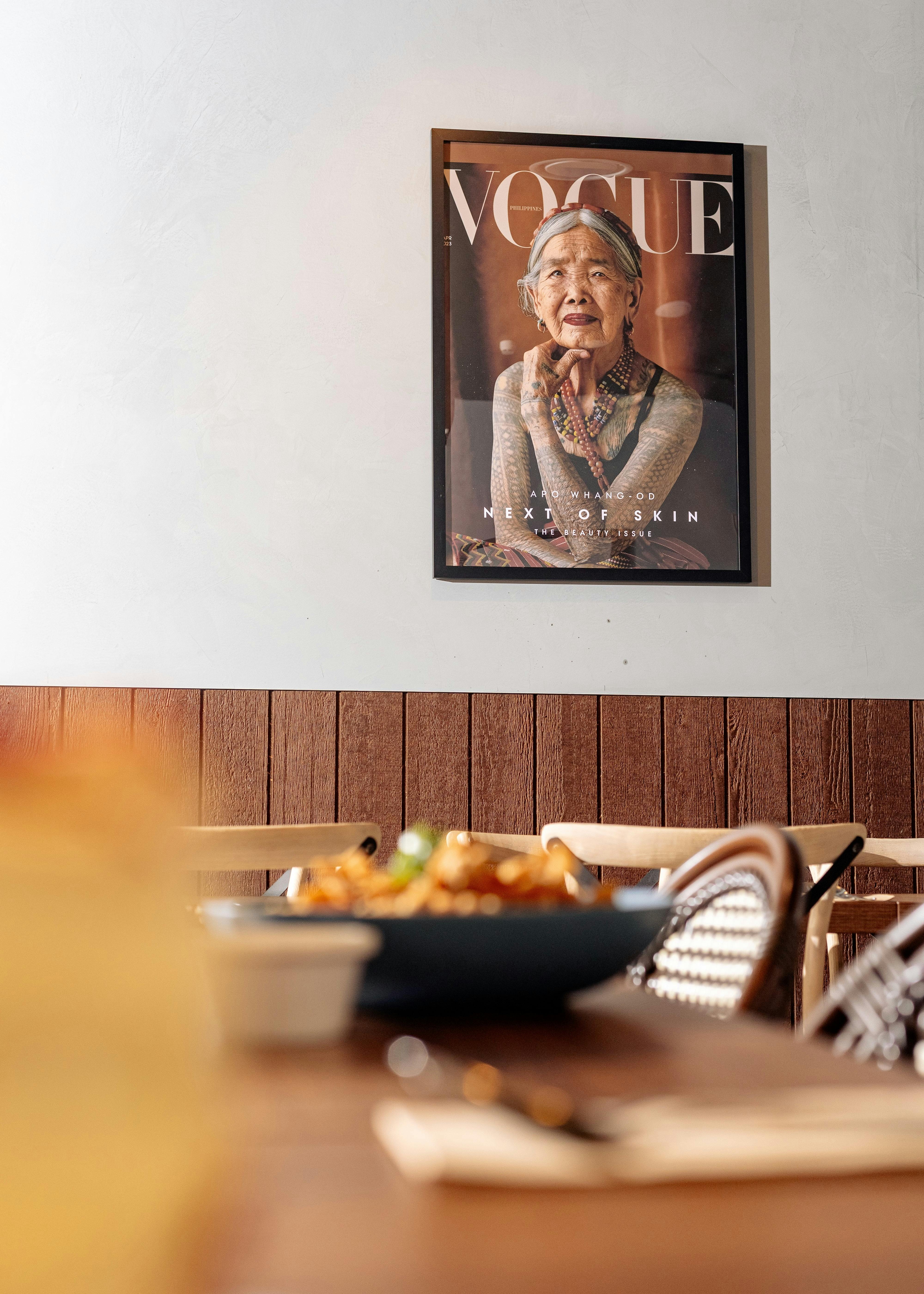 A framed magazine cover featuring a portrait of a traditionally tattooed elder, displayed above a di