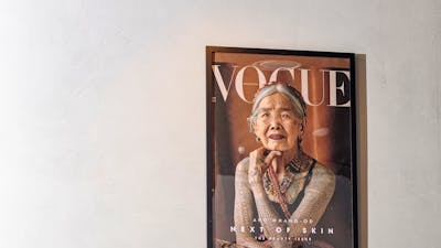 A framed magazine cover featuring a portrait of a traditionally tattooed elder, displayed above a di
