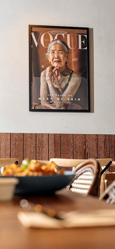 A framed magazine cover featuring a portrait of a traditionally tattooed elder, displayed above a di