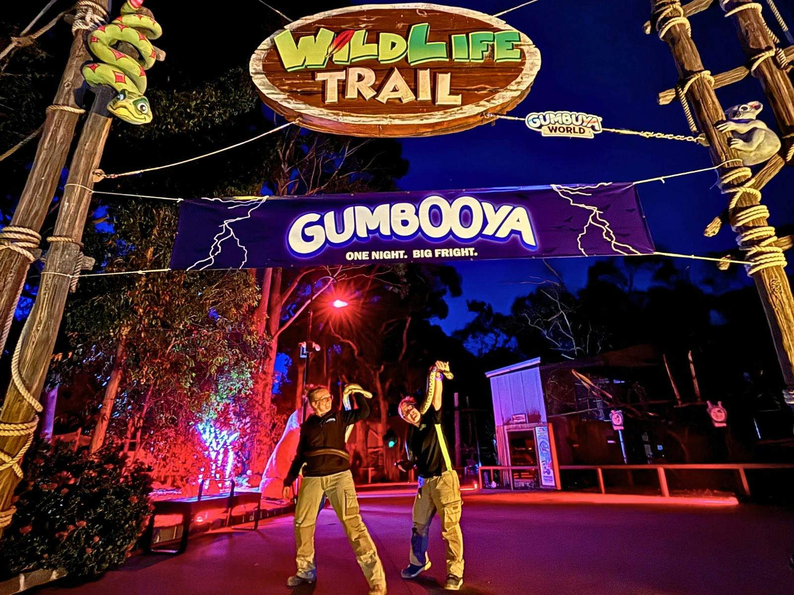 Gumbuya Rangers with snakes stand outfront Haunted Wildlife Trail with GumBOOya sign