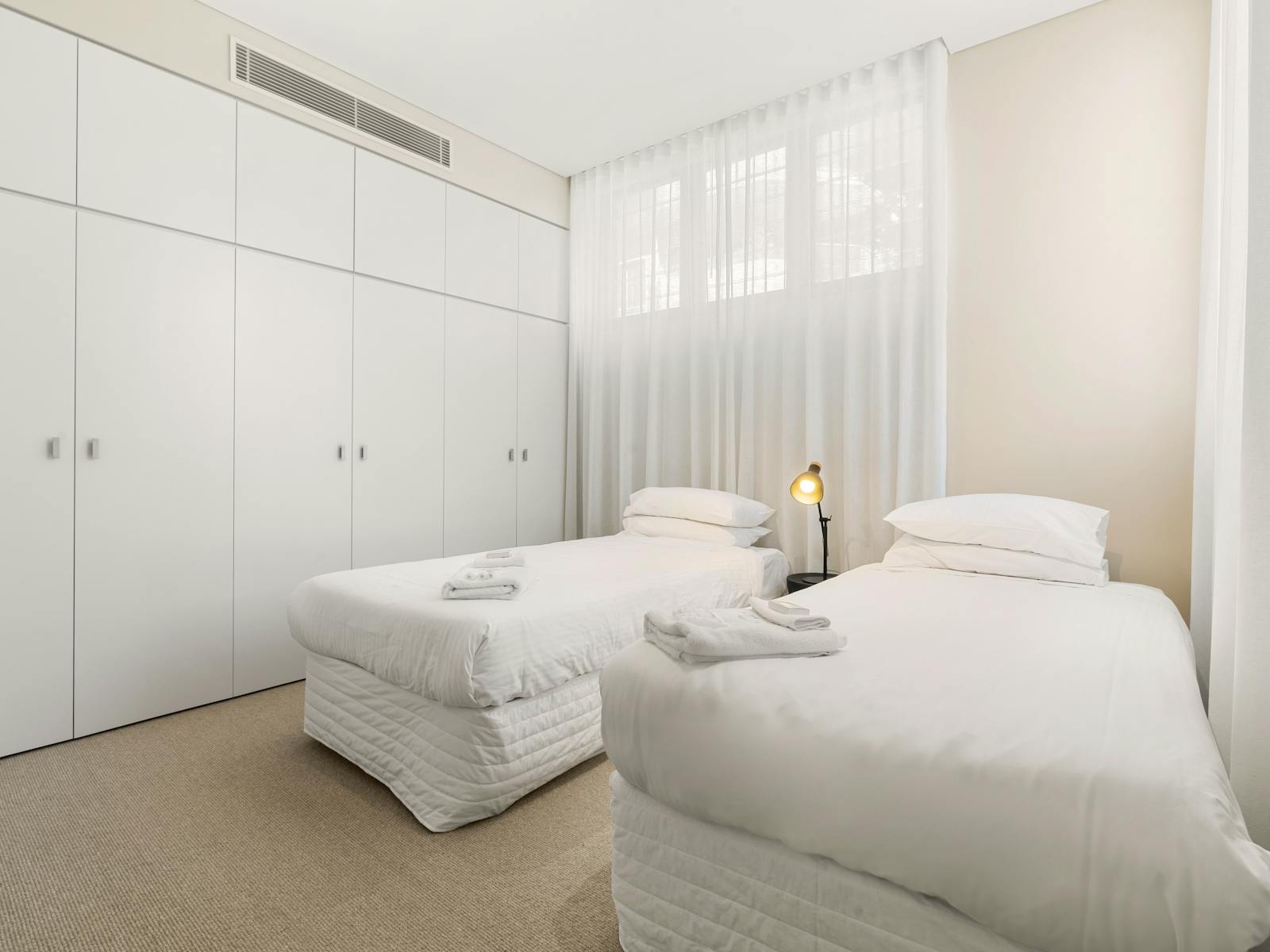 Bedroom with twin beds and minimalist furniture, perfect for restful stays.
