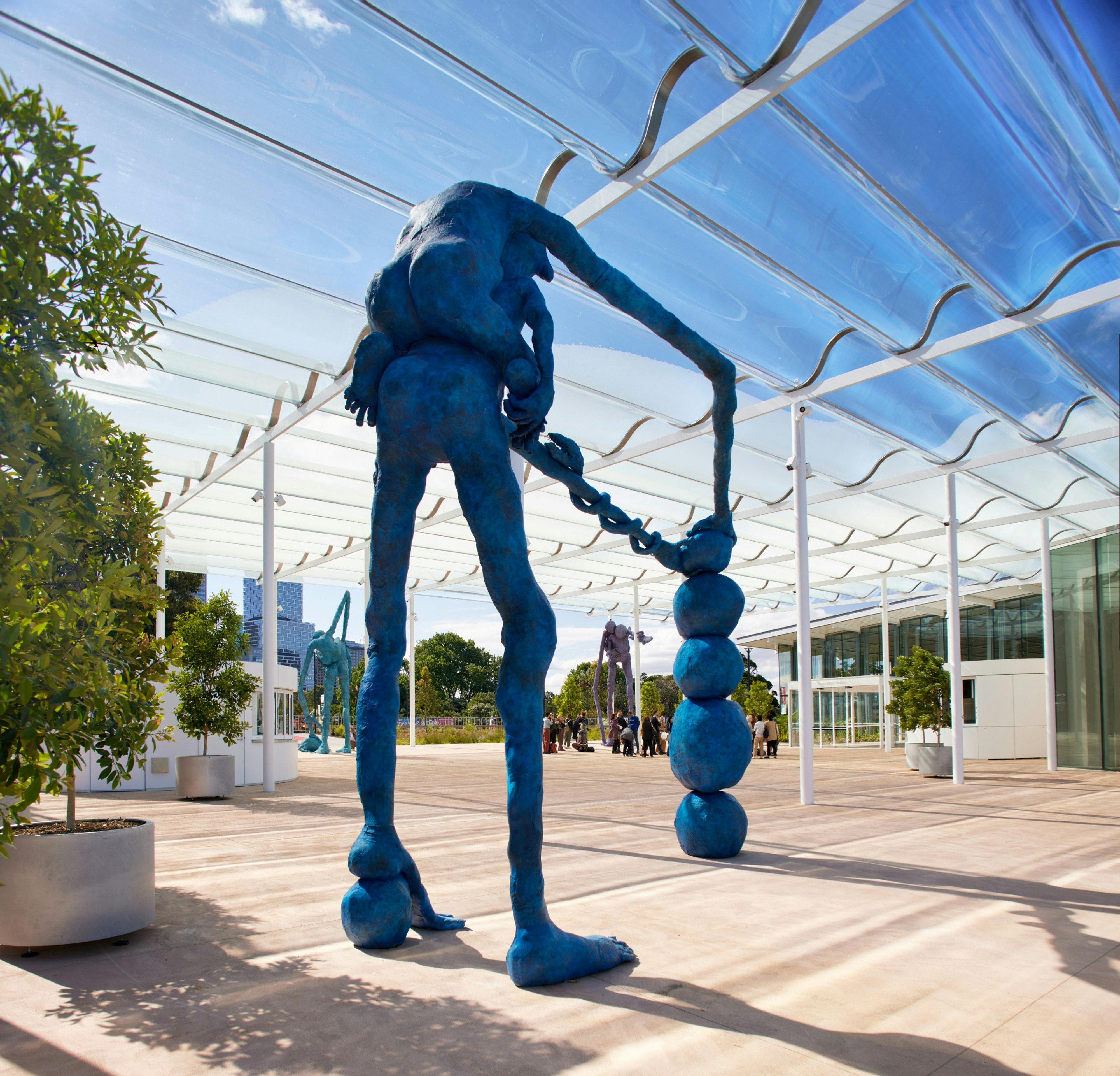 A statue of a person holding several blue balls