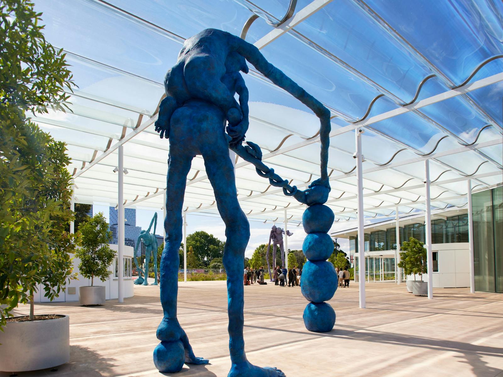 A statue of a person holding several blue balls