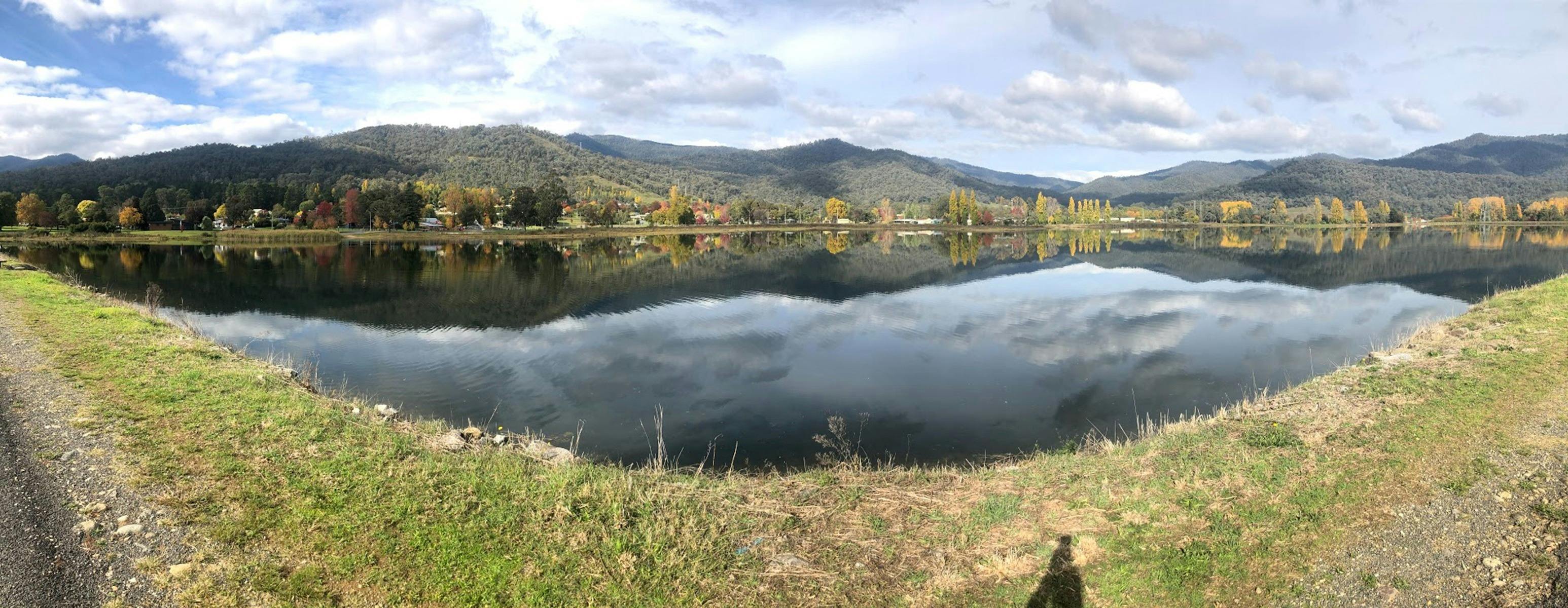 Panoramic shot of a lake with mountains and trees in the background