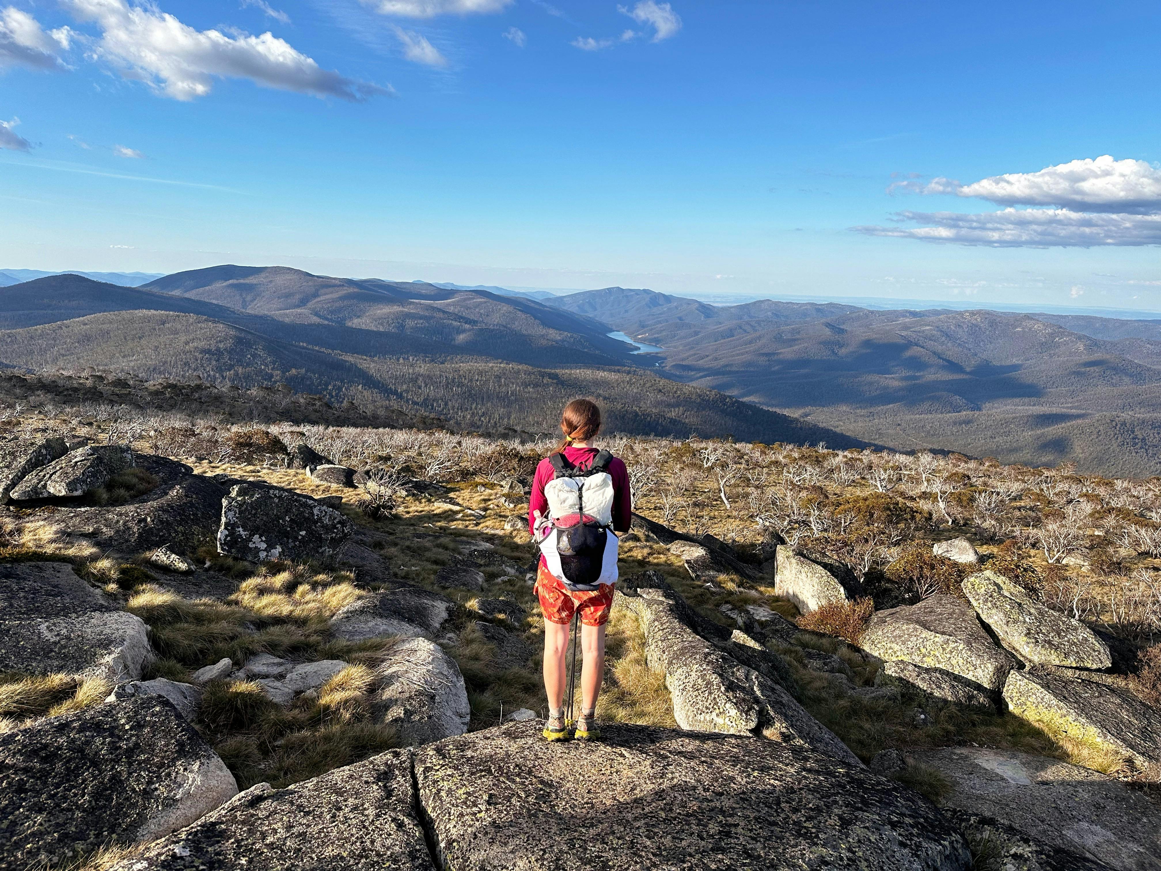 A hiker at the top of a mountain looking down onto a lake.