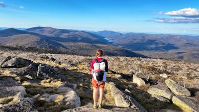 A hiker at the top of a mountain looking down onto a lake.
