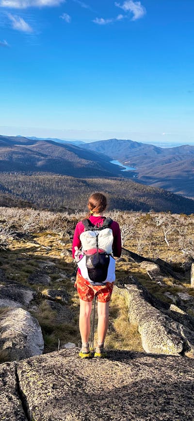 A hiker at the top of a mountain looking down onto a lake.