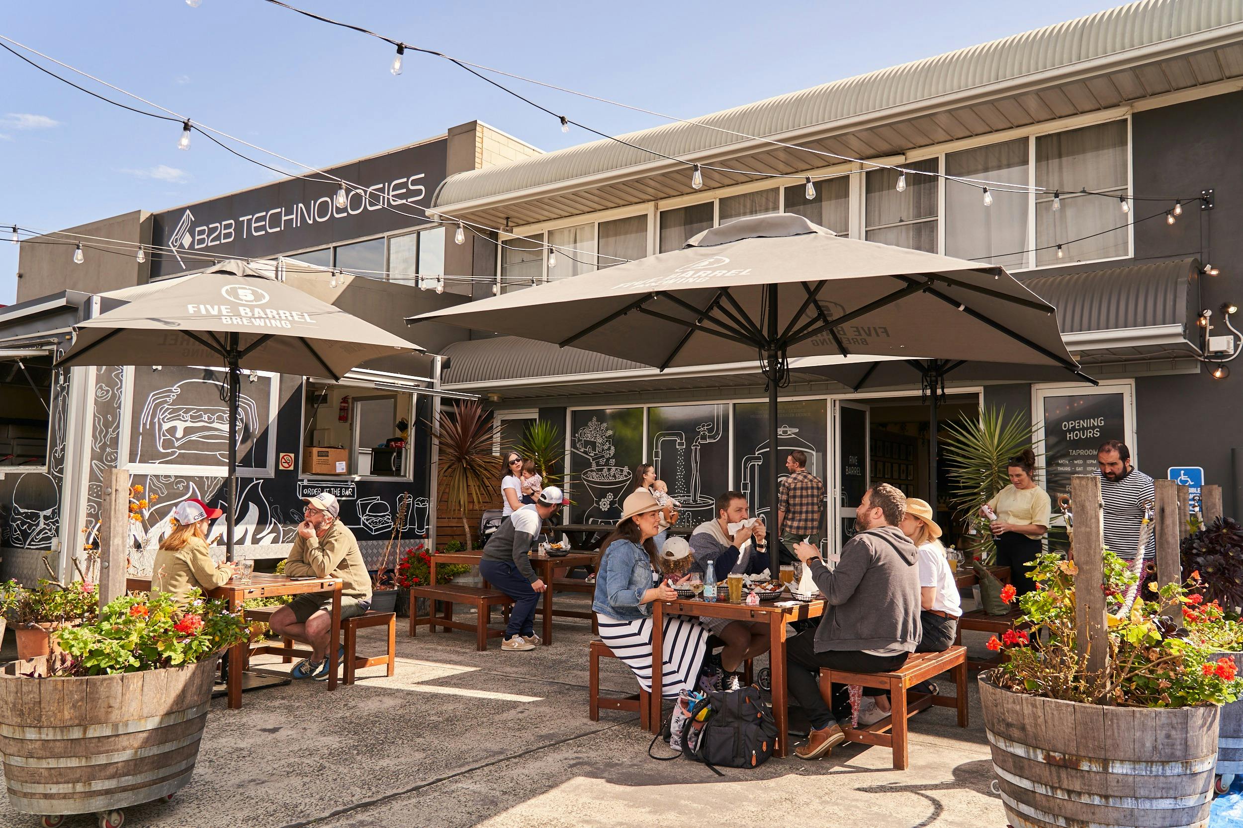 Outdoor seating at Five Barrels with umbrellas, garden, food truck, dog friendly