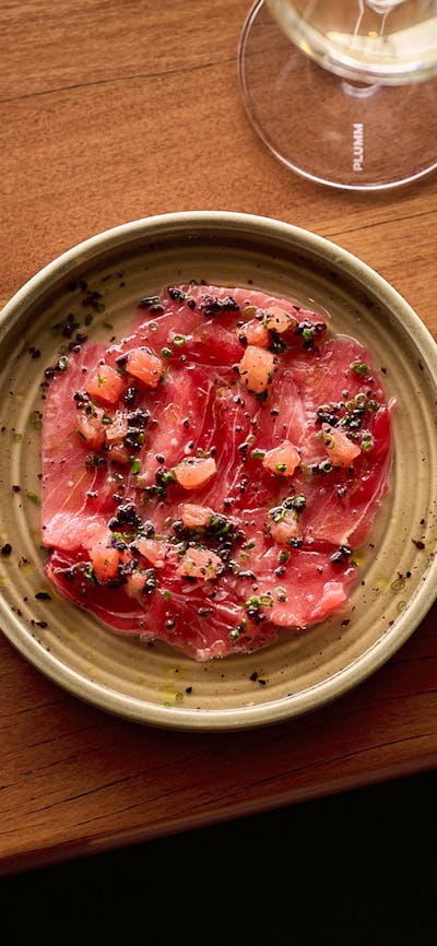 Market Fish Crudo served with a glass of white wine