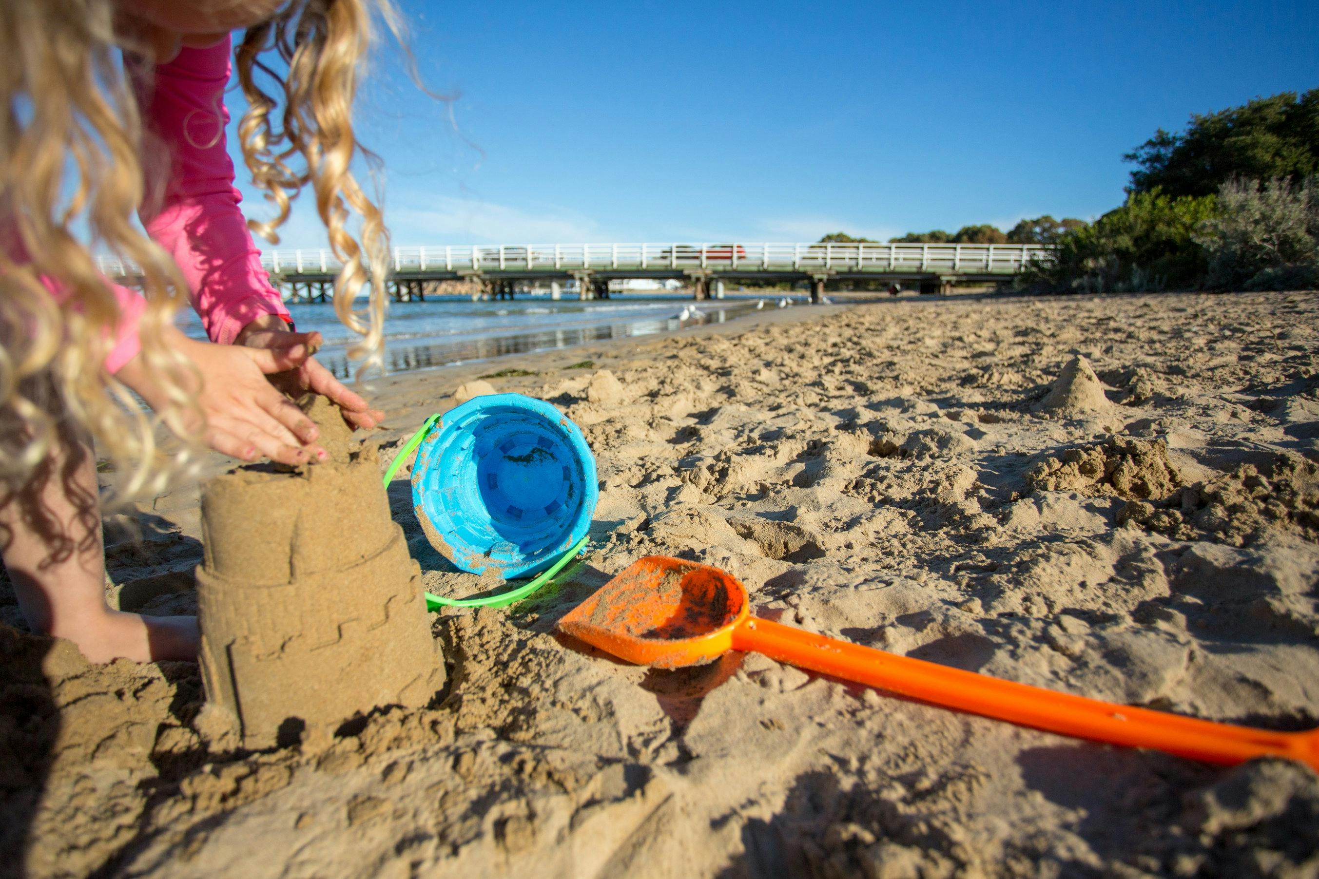 A small child making sandcastles on the Barwon River estuary beach