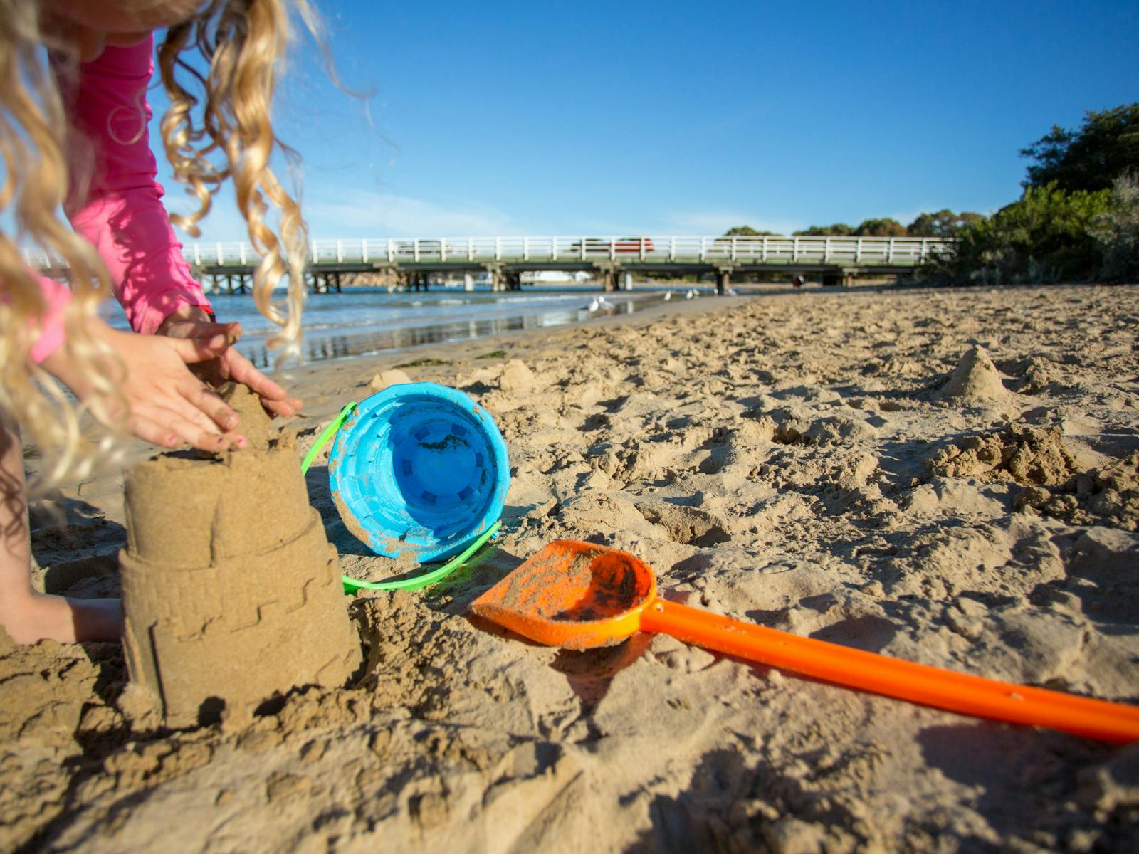 A small child making sandcastles on the Barwon River estuary beach