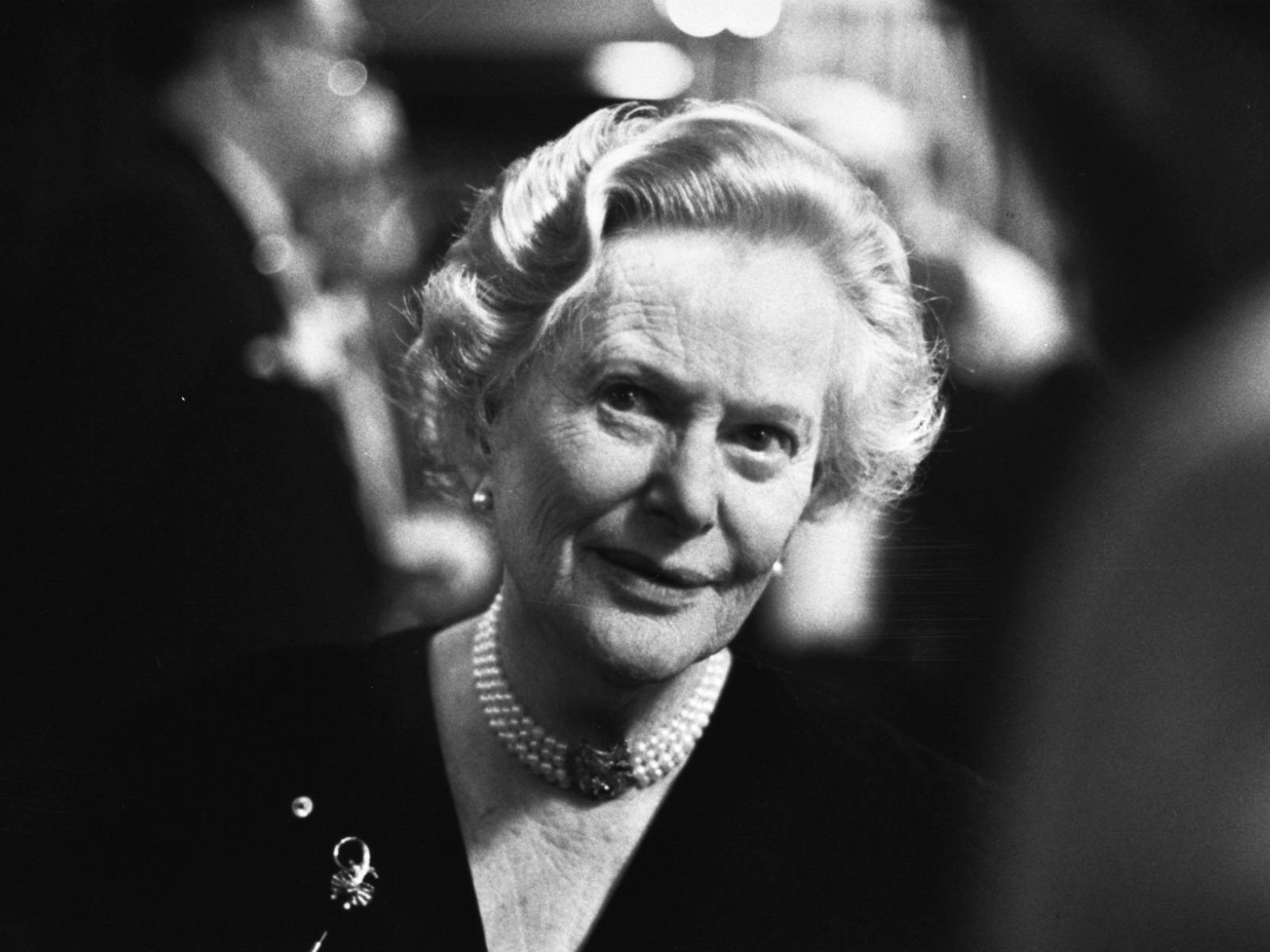 Older woman wearing pearls around neck looking past camera, black and white photo