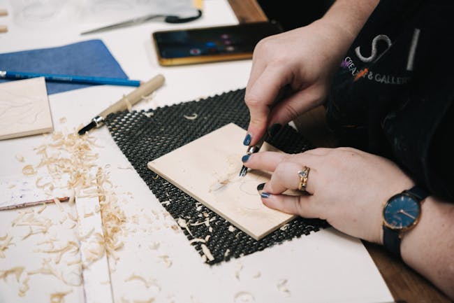 a hand carving a block of wood for a woodblock print
