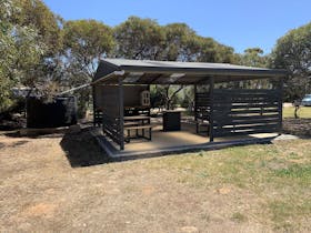 A covered outdoor barbecue and picnic area at Cummins Park and Cabin Park, featuring sheltered seati