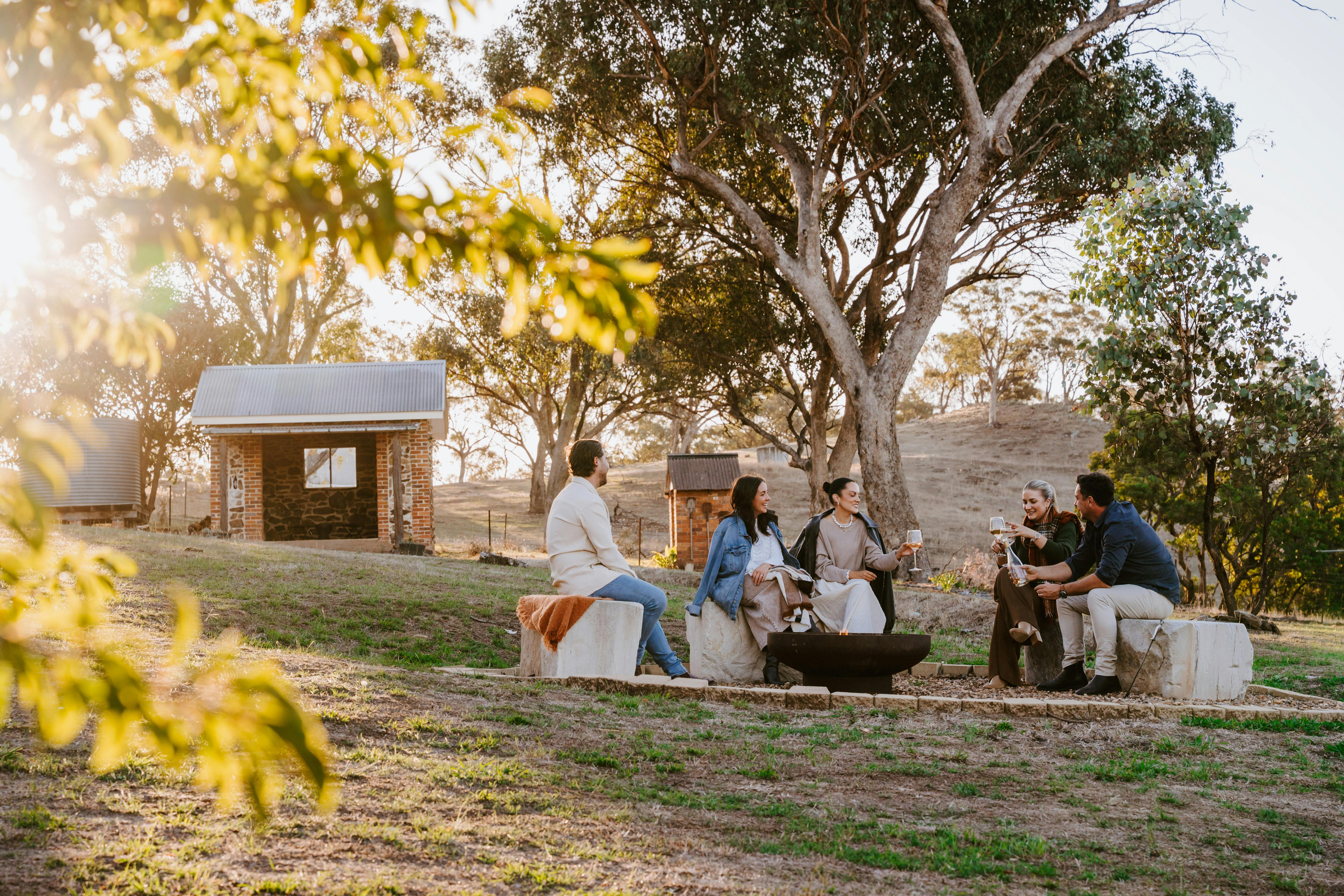 Five adults enjoying a wine around the firepit