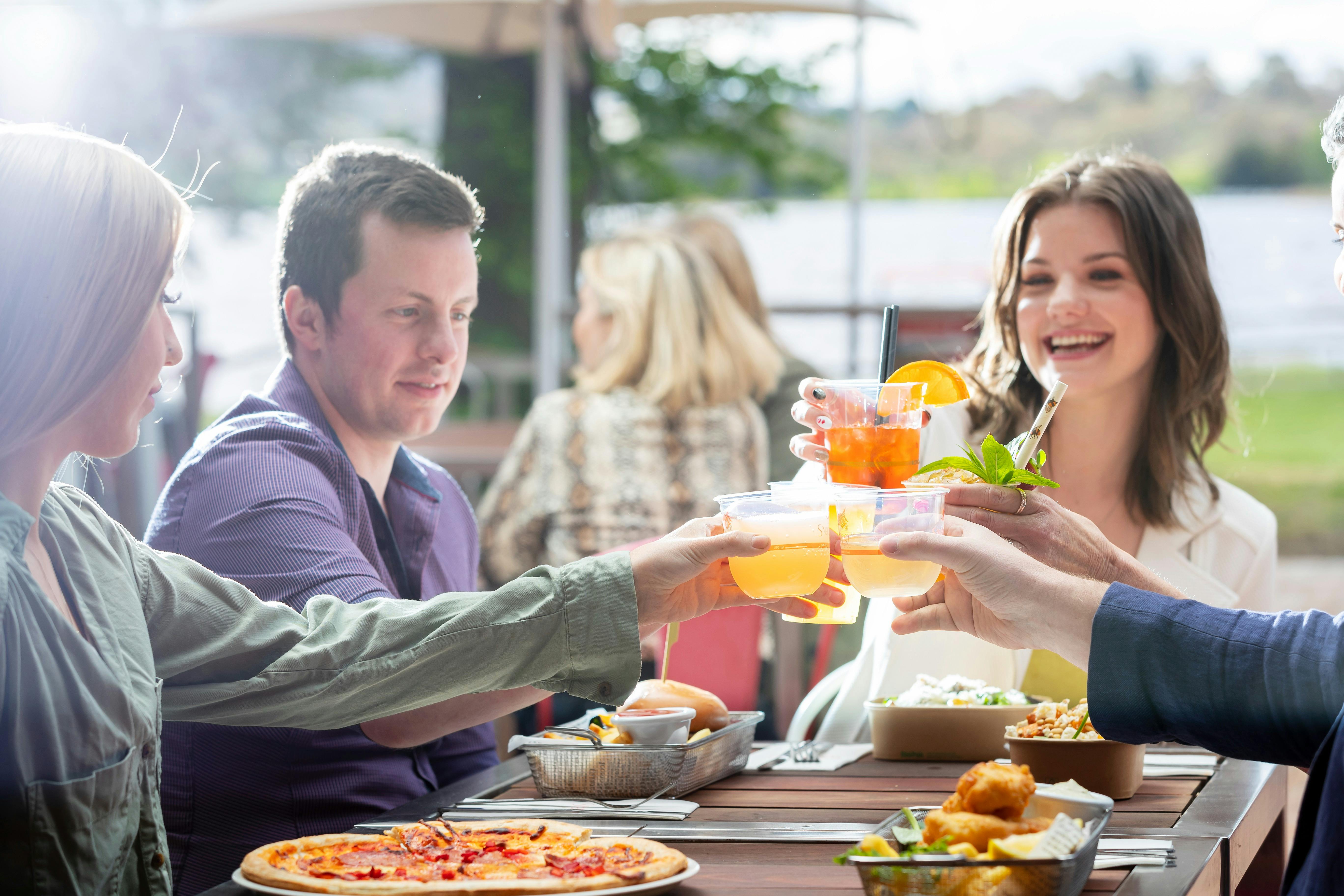 Group of adults clinking glasses at a lunch setting