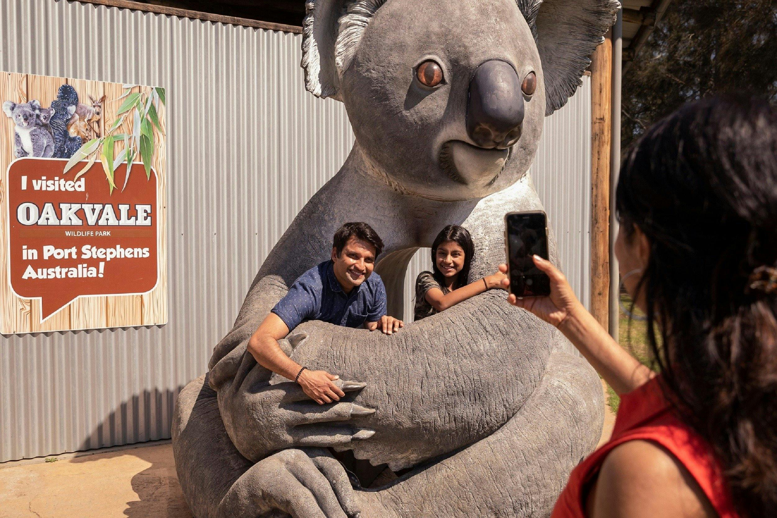 A father and child in a giant koala having their photo taken by the mother on her phone