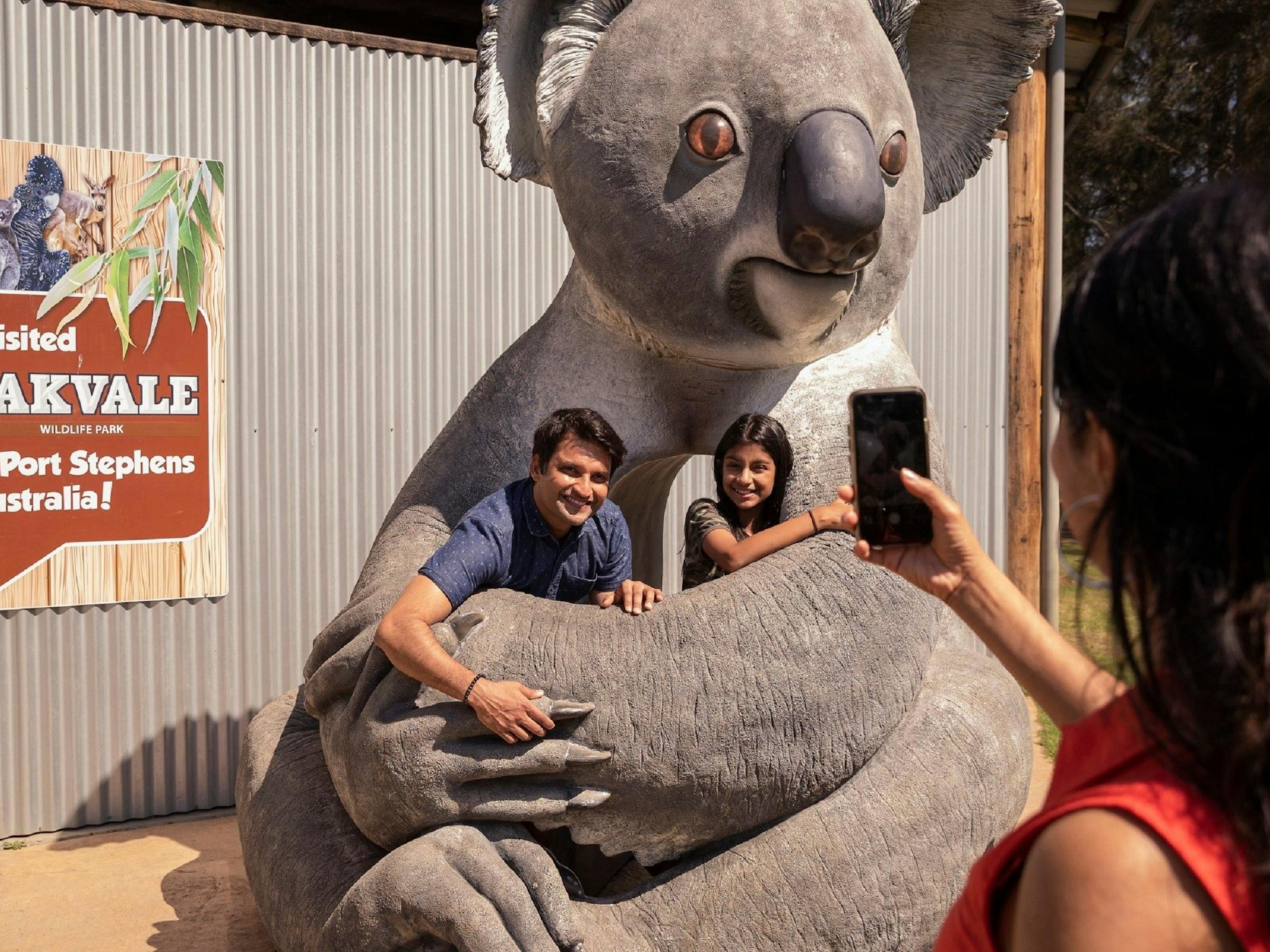 A father and child in a giant koala having their photo taken by the mother on her phone