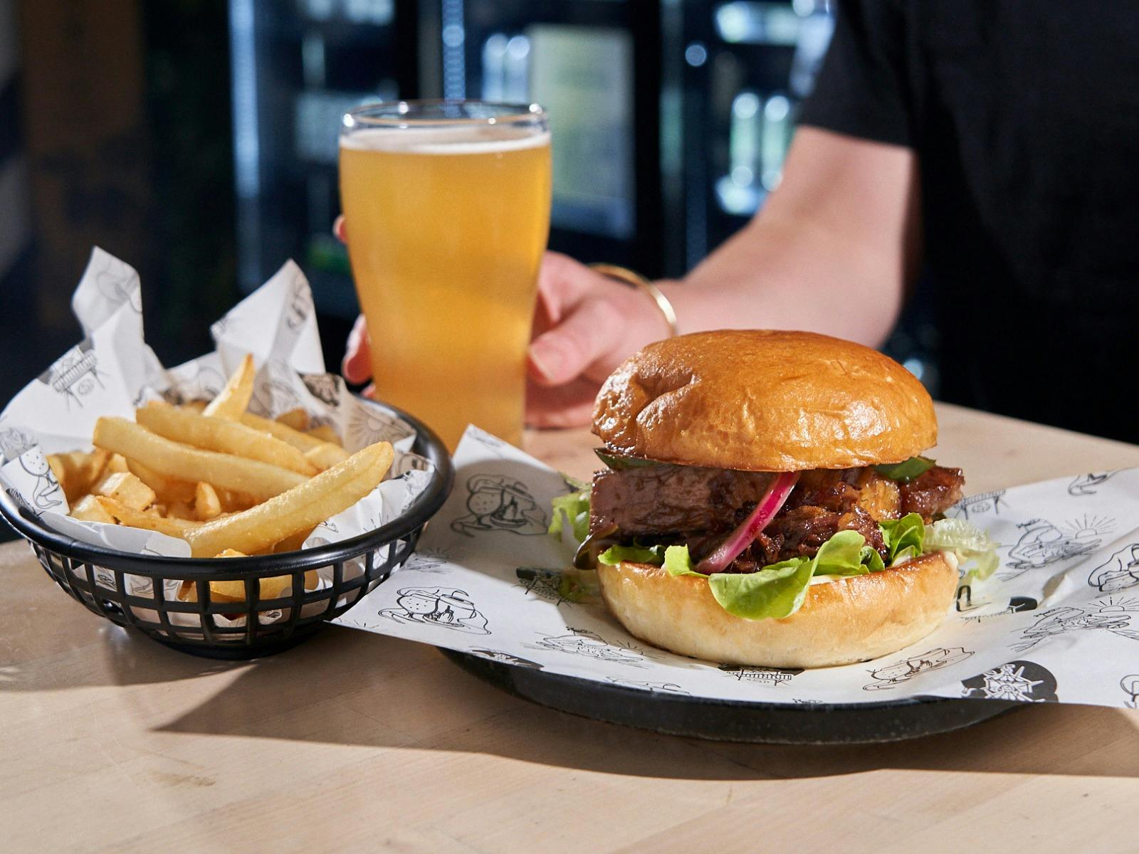 A delicious looking burger, chips and schooner of beer