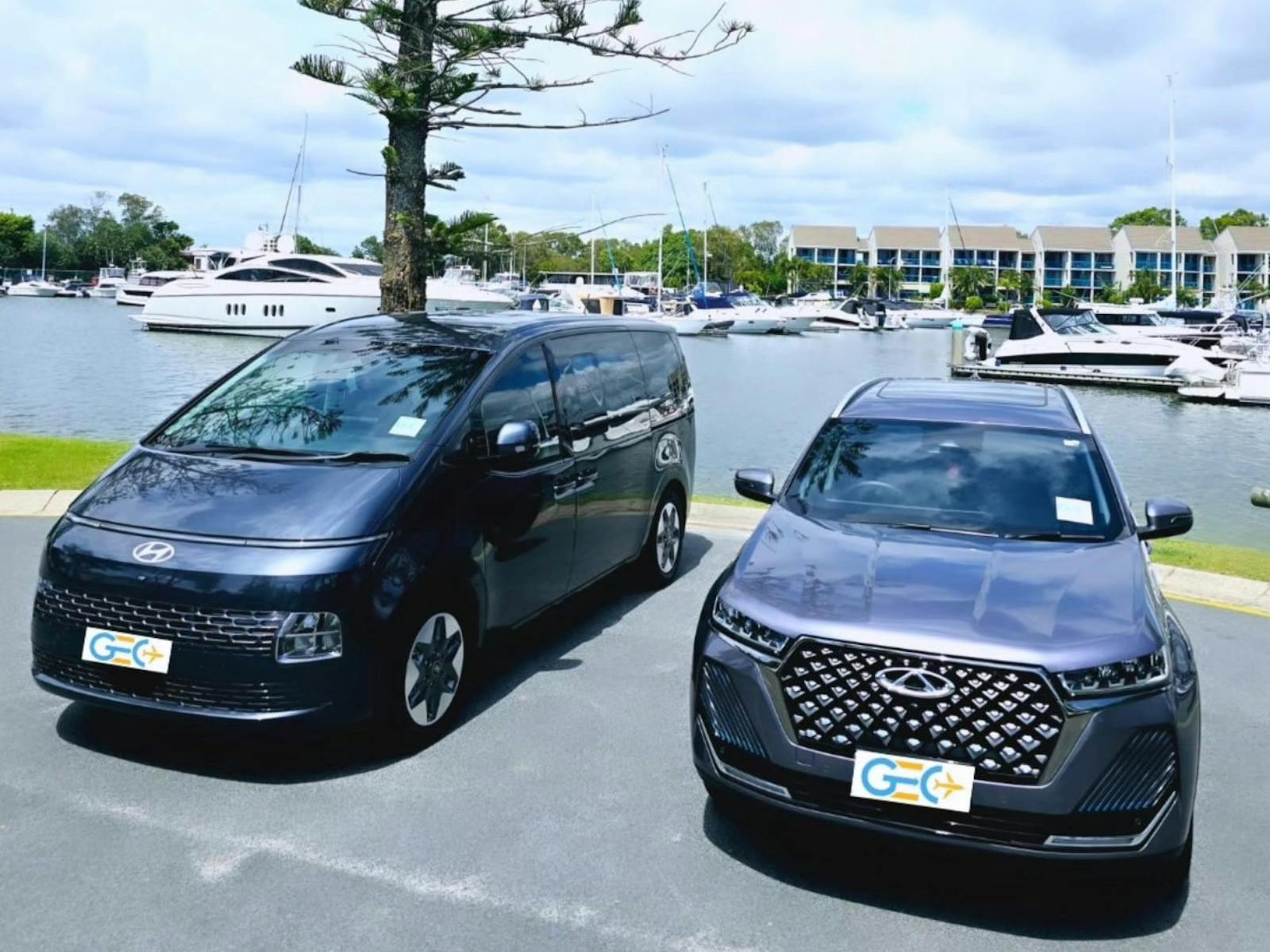 Hyundai van and Chery SUV from GEC Transfers parked near a marina with yachts and waterfront Hyundai van and Chery SUV from GEC Transfers parked near a marina with yachts and waterfront