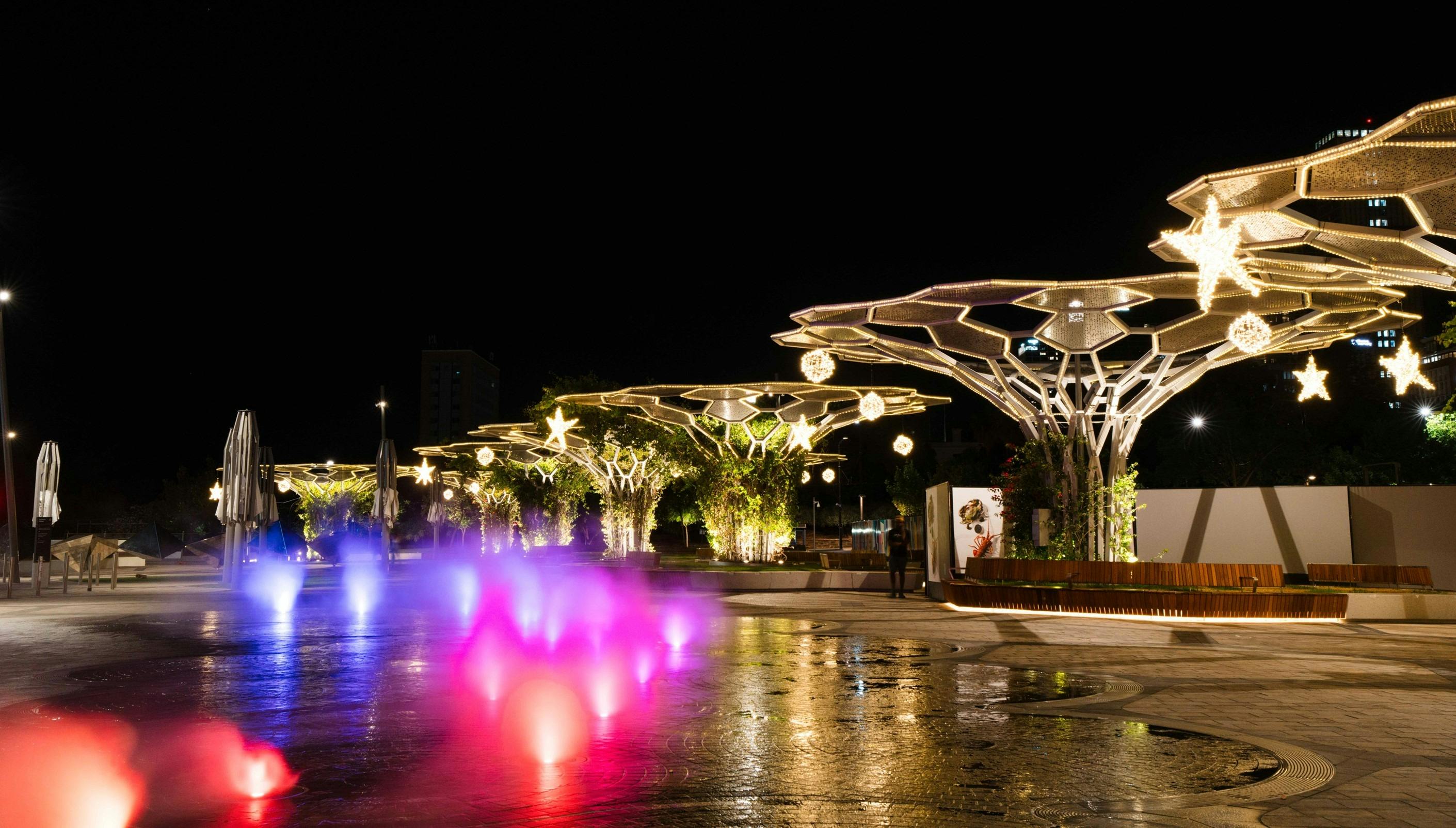 Arbours covered in rope lighting with hanging baubles and stars.