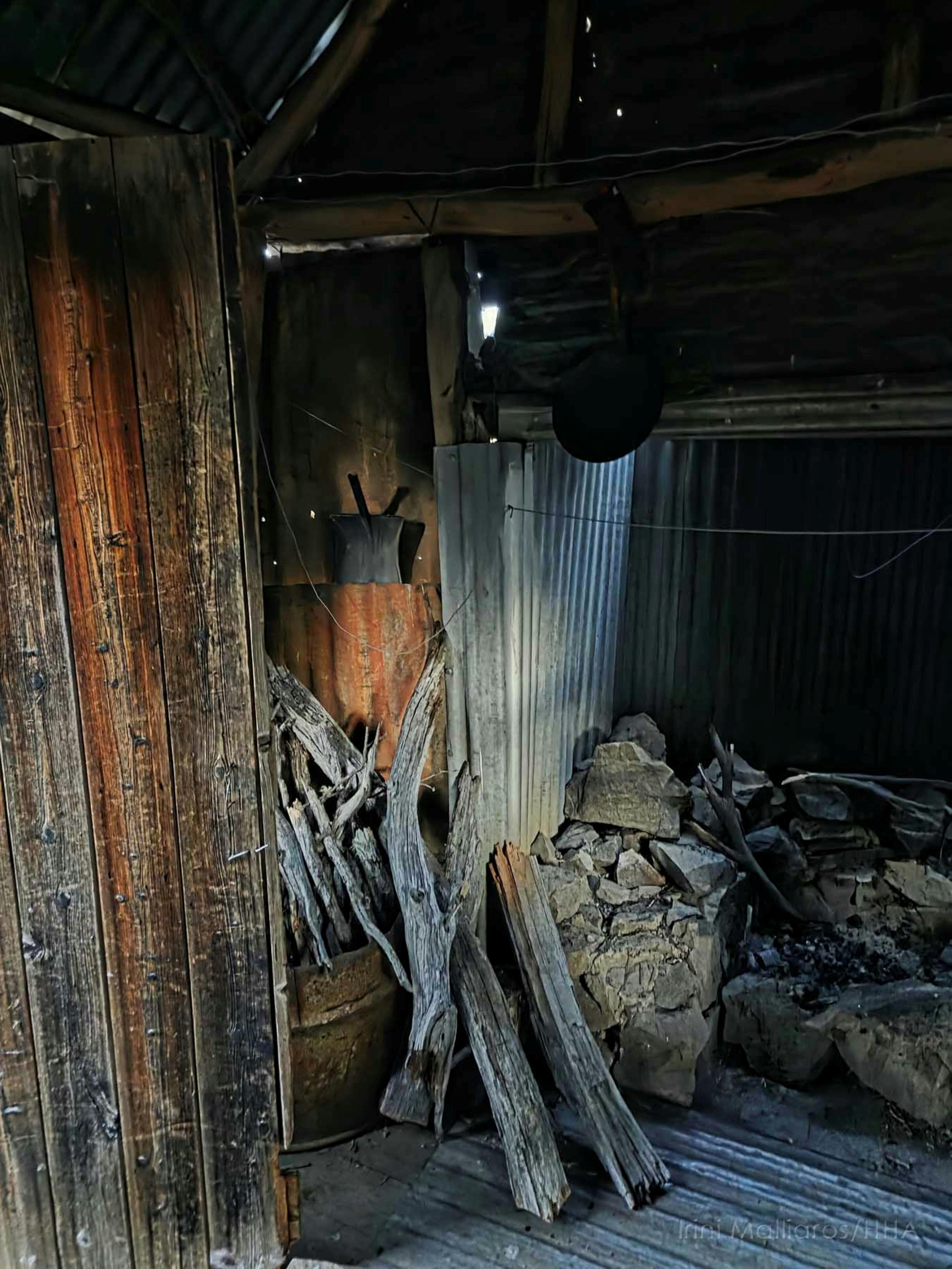Interior of mountain hut showing firewood and a stone fireplace
