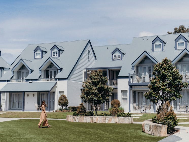 A woman walking on the lawns in front of Hamptons-style accommodation