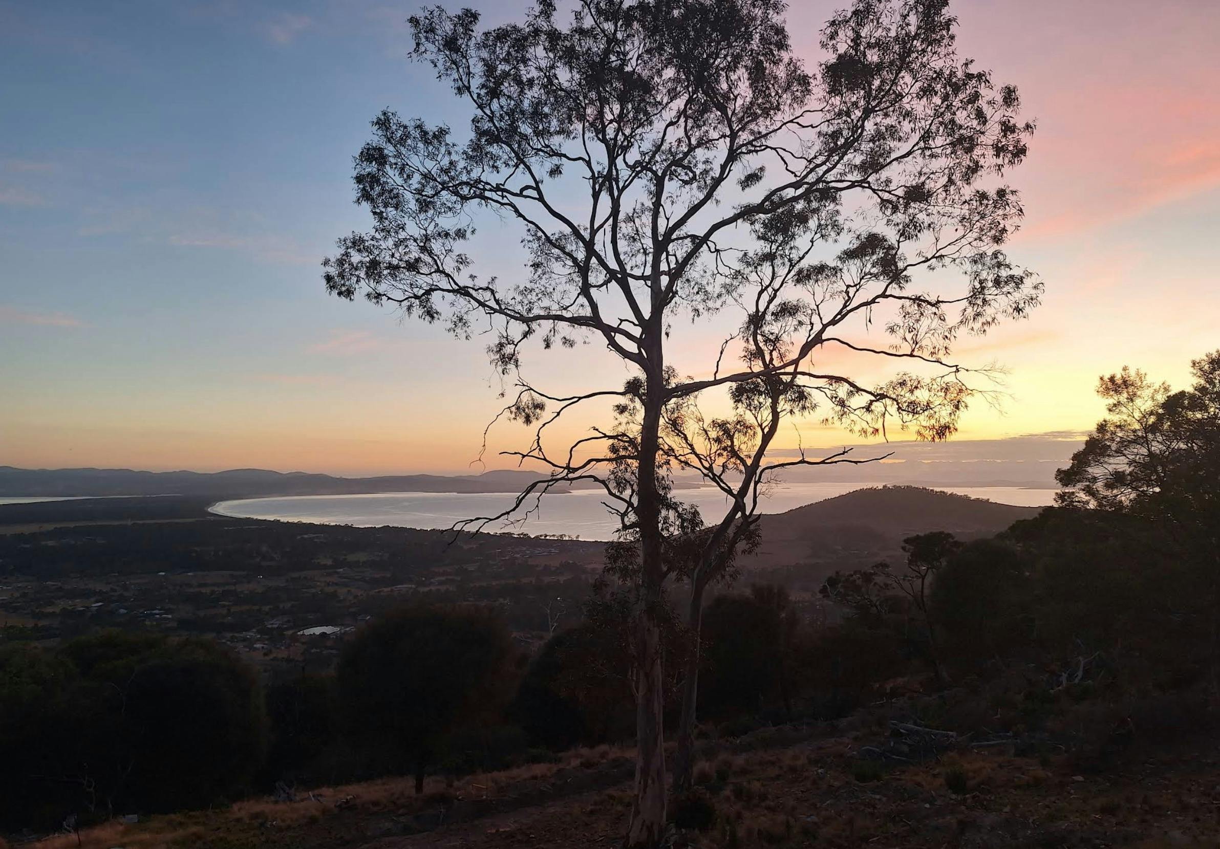 Sunset over the bushland and distant landscape at Mt Rumney