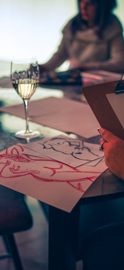 Drawing of naked humans next to a glass of wine