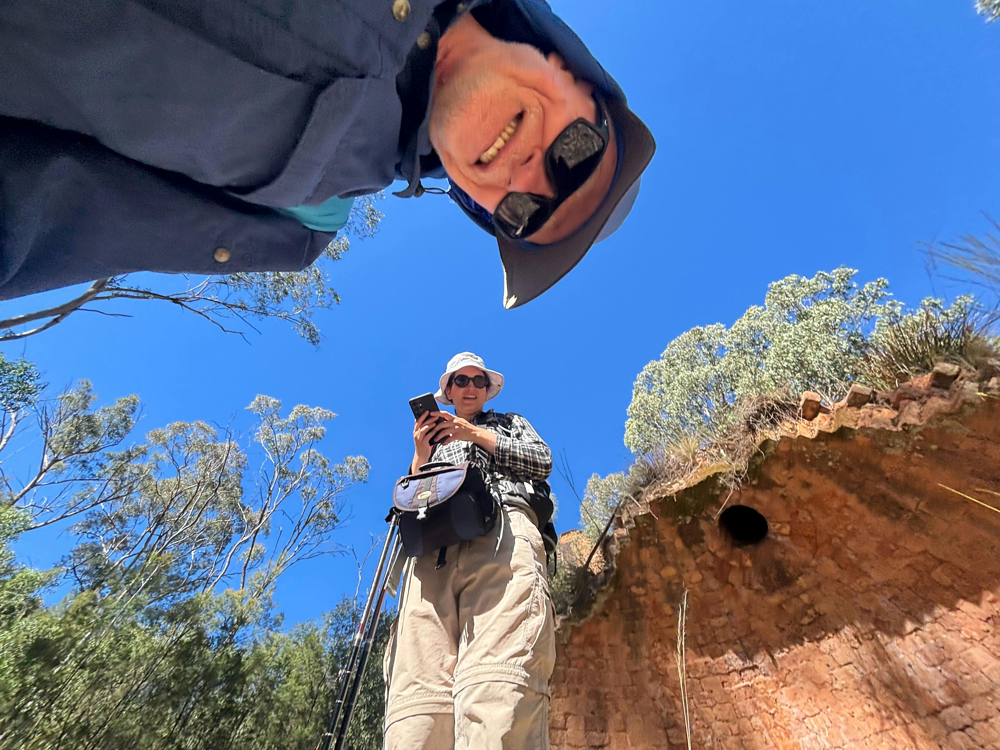 A man and a woman staring down at a camera taht has captured their image beneath a blue sky