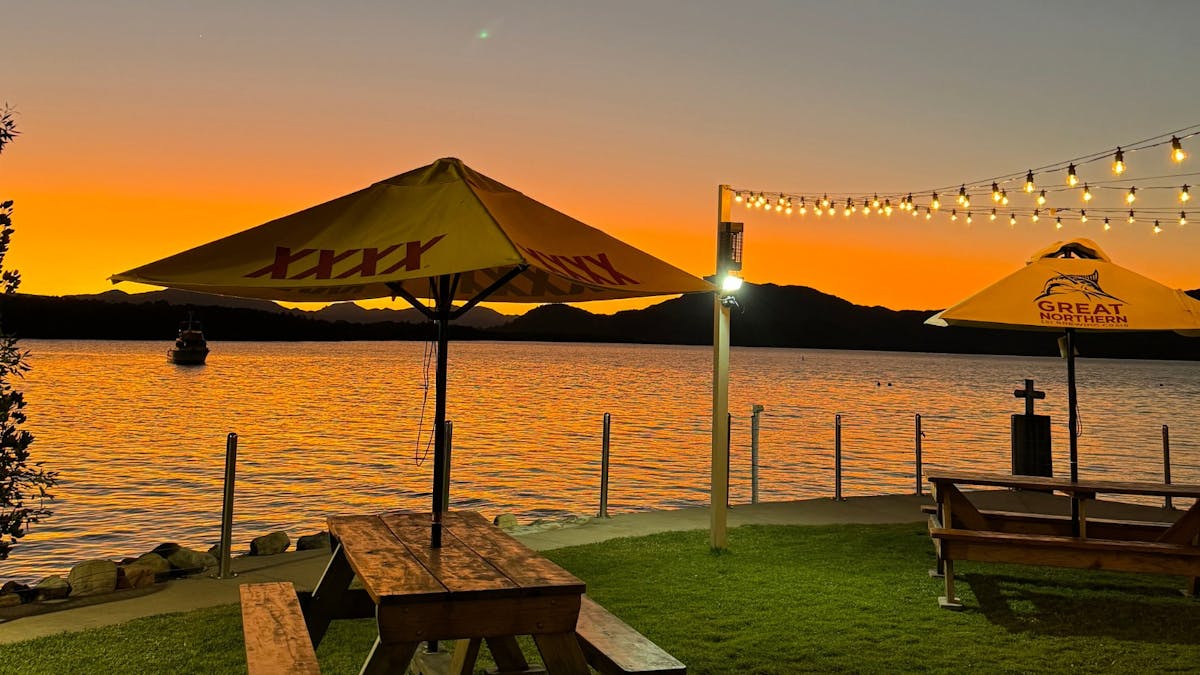 Sunset over water, with picnic tables and fairy lights
