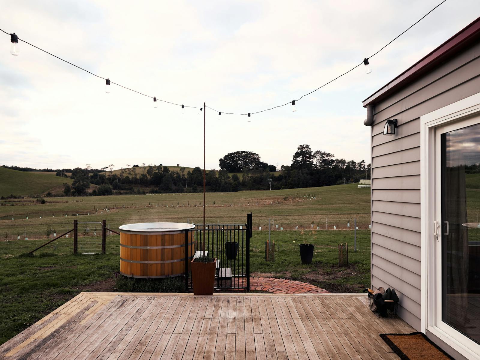 bac of house with timber deck, hot tub and festoon lights