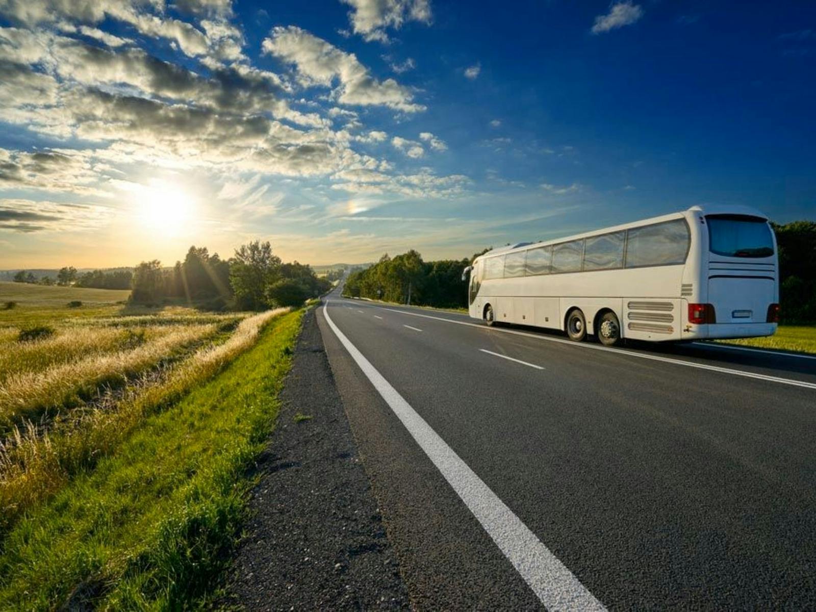 Image of a bus on a road with the sunset in the background