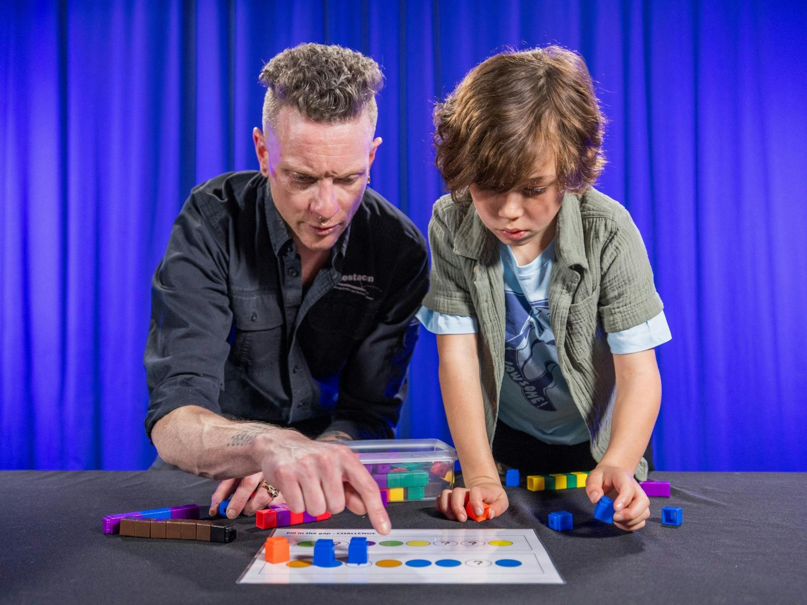 A man and a boy explore patterns using coloured blocks